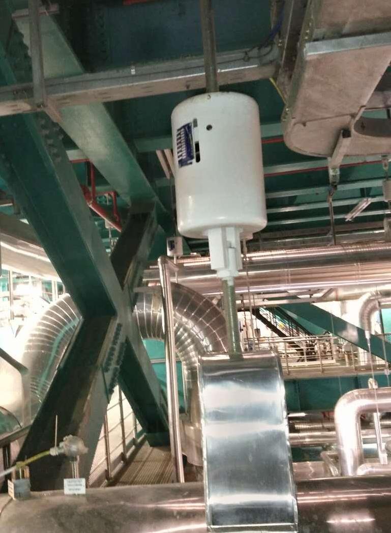 White constant support hanger installed under plant steelwork, suspending a large insulated pipe