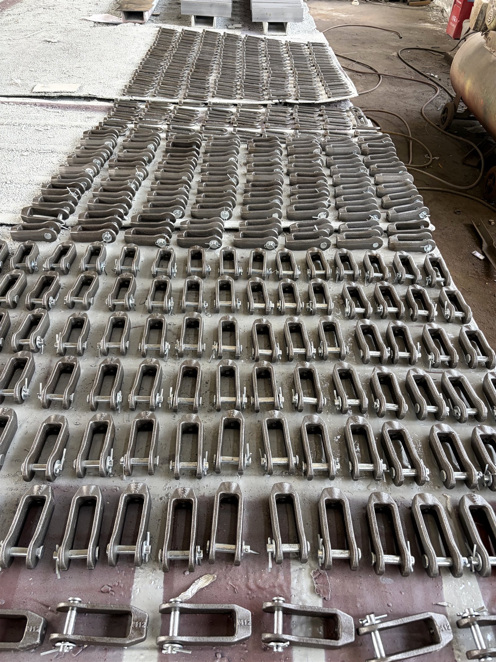 Rows of drop-forged clevises and hanger hardware drying after primer at the forging section
