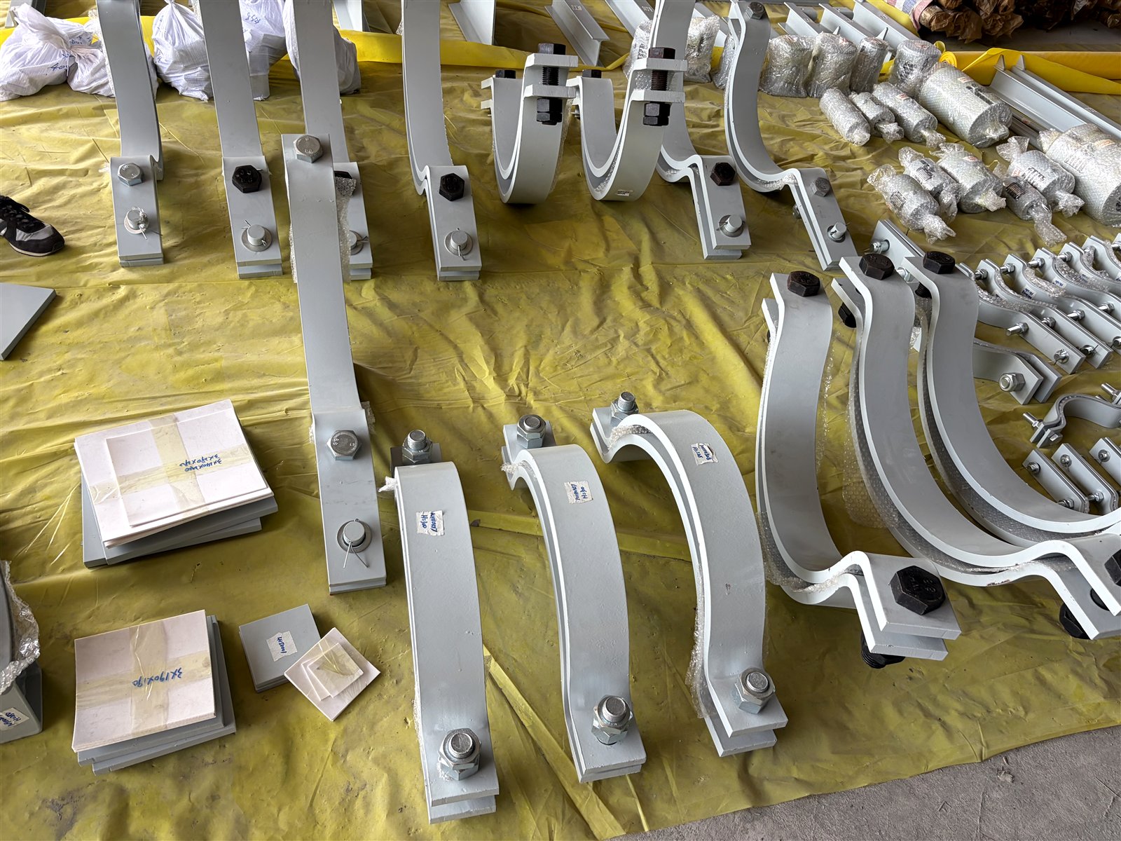 Large-bore insulated pipe clamps with slide plates and tagged components ready for packing