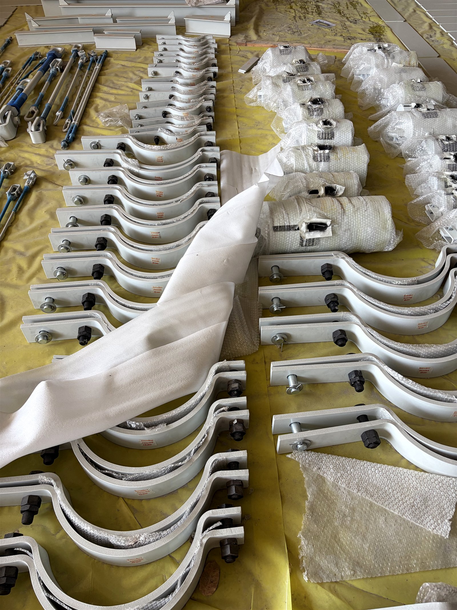 Rows of tagged pipe clamps with hardware fitted, laid out for pre-dispatch inspection